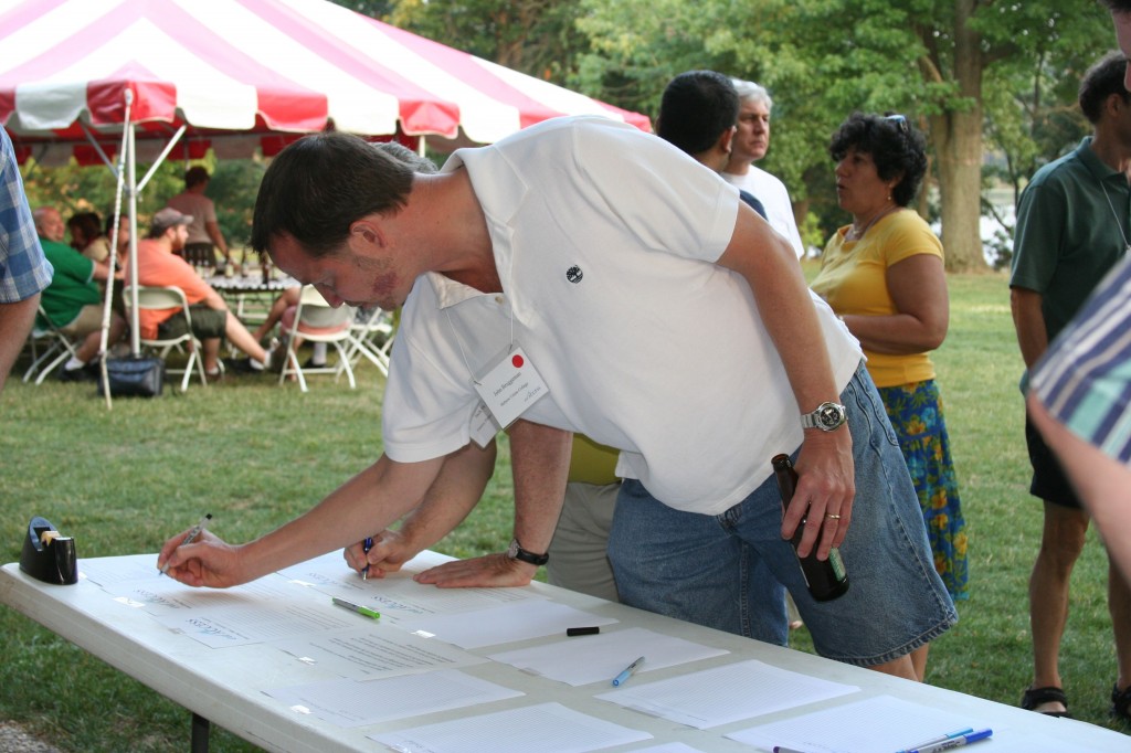 onsite crowdsourcing events: a photograph of an attendee signing up for sessions lusted on an outdoor table
