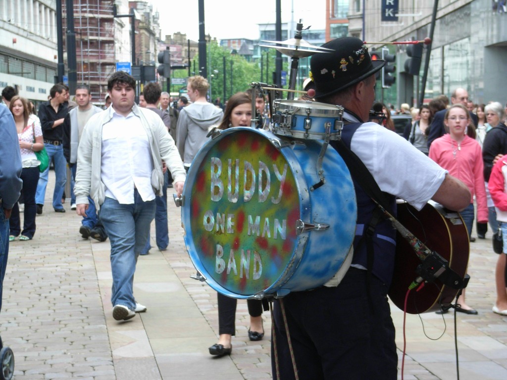 successfully self-employed: a photograph of a busker playing multiple instruments on a busy street