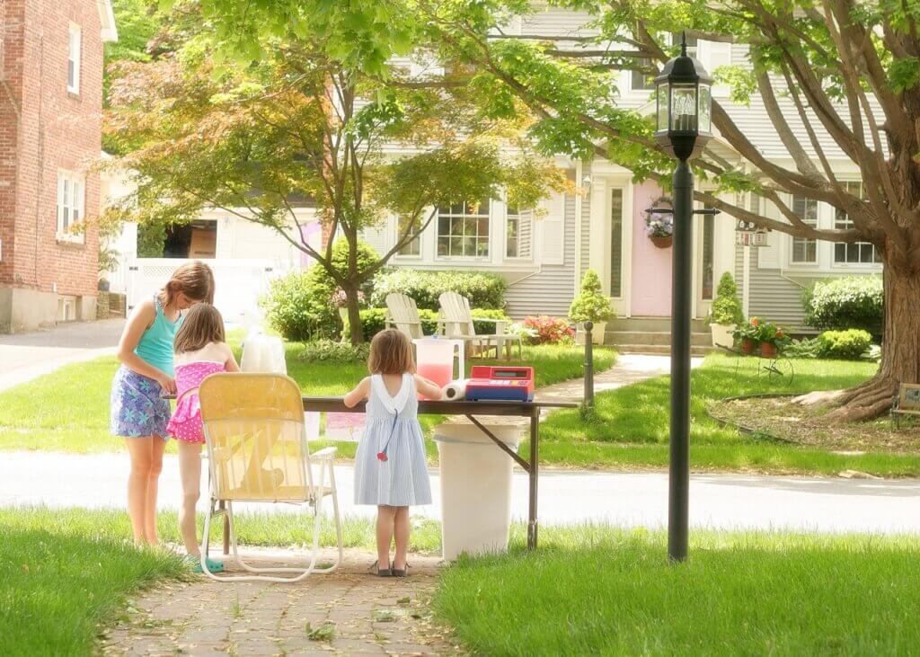 mom killed that idea: photograph of three girls setting up an outdoor lemonade stand