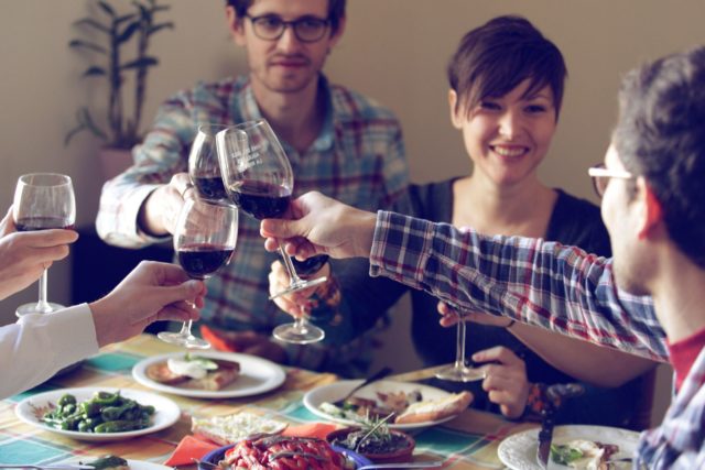 supporting connection: photograph of four people at a dinner table toasting each other with glasses of wine. Image attribution: recode.net