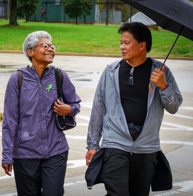 incorporate exercise into event programs: photograph of two people walking, smiling, and talking in the rain