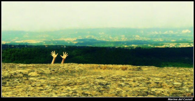 asking for help: A photograph of two outstretched hands with fingers spread appearing above a hill in a barren landscape. Photo attribution:  Flickr user marinadelcastell