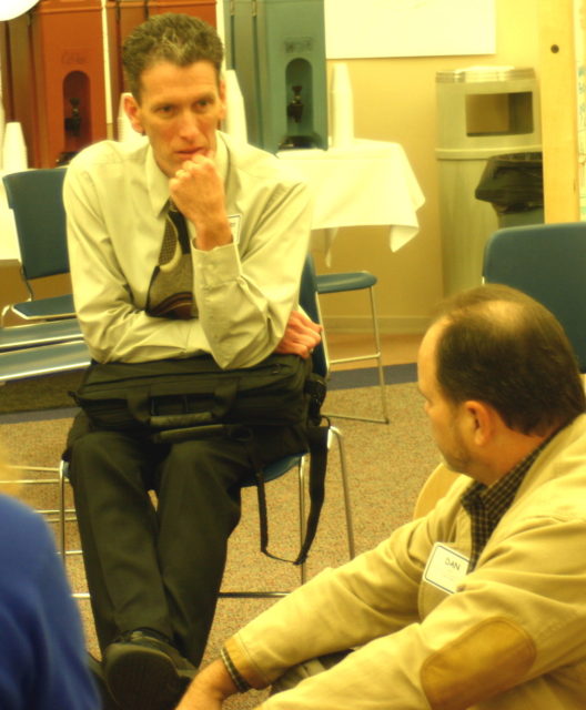 facilitation rapt attention and love: photograph of two men wearing name badges sitting and talking indoors