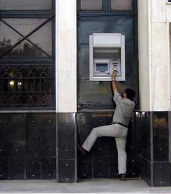 hire best professional help: photograph of a man trying to access an ATM that has been installed too high off the ground