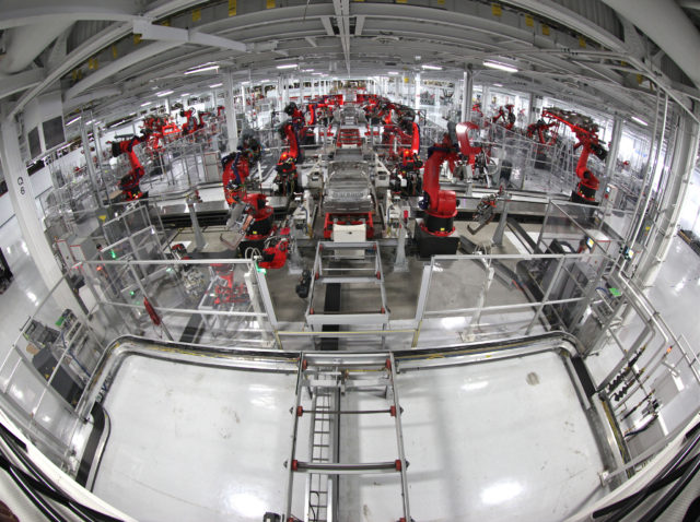 The end of decent paid jobs and the need for basic income: a fisheye view photograph of a production line of industrial robots devoid of humans. Photo attribution: Flickr user jurvetson.