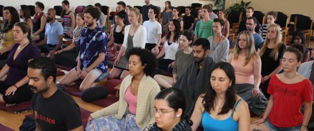 The interpersonal dynamics of silent retreats: a photograph of a group of people silently meditating, sitting indoors, on the floor