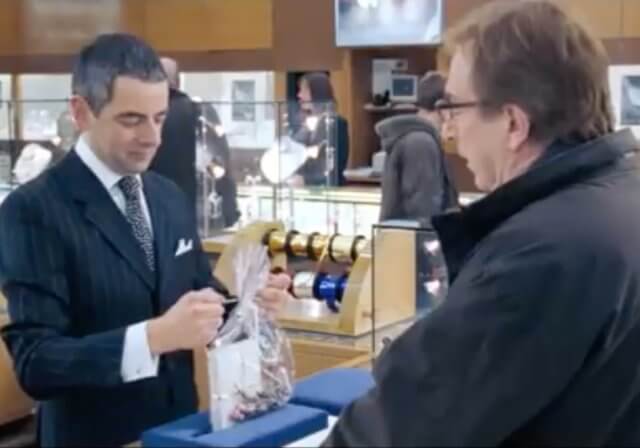 What's most important about an event?: a screenshot from the movie Love Actually (2003). With his wife shopping nearby, Harry (Alan Rickman) impulsively purchases an expensive necklace for his mistress — only to be tortured by the fear of discovery as Rufus (Rowan Atkinson) slowly wraps his gift.