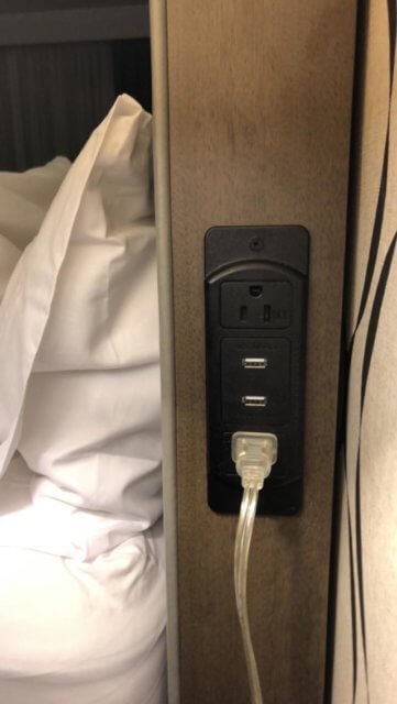 Power in hotel rooms: a photograph of two power outlets and two USB ports installed at the head of a hotel bed