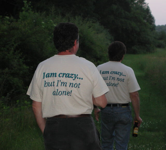 not crazy not alone: a photograph of two edACCESS participants walking away from the camera outside in a field. They are both wearing tee shirts that say "I am crazy…but I'm not alone!"