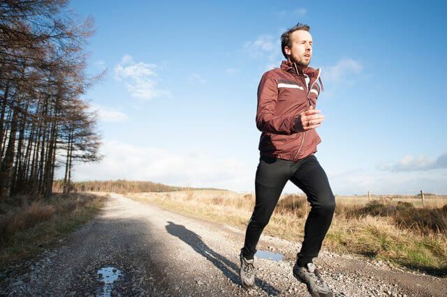 The first hill is the hardest: a photograph of a man running on a flat country dirt road. Photo attribution: Jenny Hill jennyhill [CC0], via Wikimedia Commons