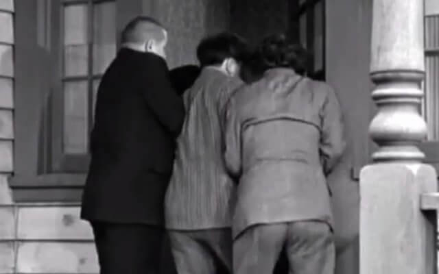 Who goes next? A black and white photograph of the backs of The Three Stooges trying to all go through a narrow doorway at the same time.