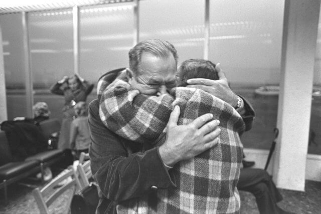 responses to adversity: black and white photograph of two elderly men hugging in an airport lounge