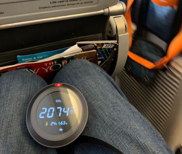 A photograph of a CO2 meter on my lap reading 2,074 ppm while deplaning in Puerto Rico, showing the poor air quality on the plane