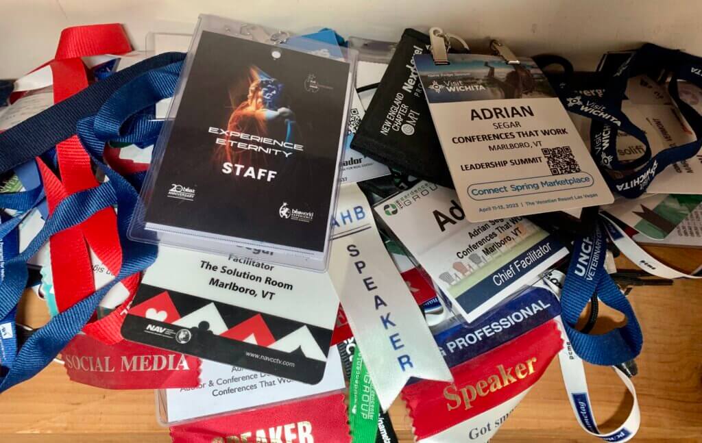 A photograph of a pile of Adrian Segar's event badges from 2023 and earlier